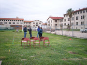 Four sanctuary staff considering the layout of the back deck of the Manta outlined with string and chairs in a field during the planning stages