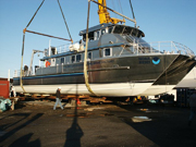 Starboard side view of the R/V Manta as it hangs suspended from a large crane.