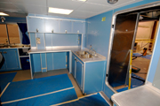 An L-shaped counter with blue cabinets beneath inside the wet lab.  To the right of the counter is a doorway leading to the main deck..