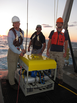 Three-man crew standing around ROV on the deck of a boat