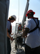 People in hard hats getting ready to launch a piece of equipment off the deck of a boat.