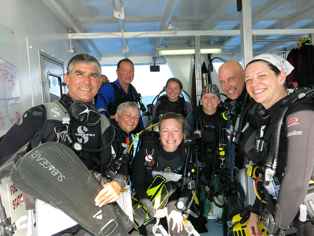 A group of 8 divers in scuba gear ready to make a dive