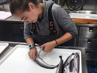 Female student cutting open a fish in a lab