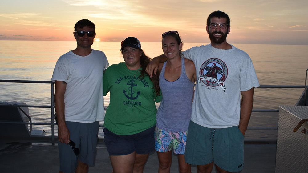 R/V MANTA crew standing on the deck at sunset.